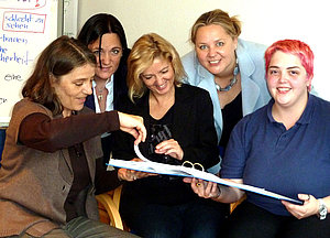 Marion Carman und 4 Frauen blättern gemeinsam eine Mappe durch