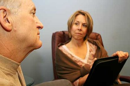 Beratungsgespräch: ein älterer Herr links blickt nachdenklich, während die Beraterin rechts im aufmerksam zuhört